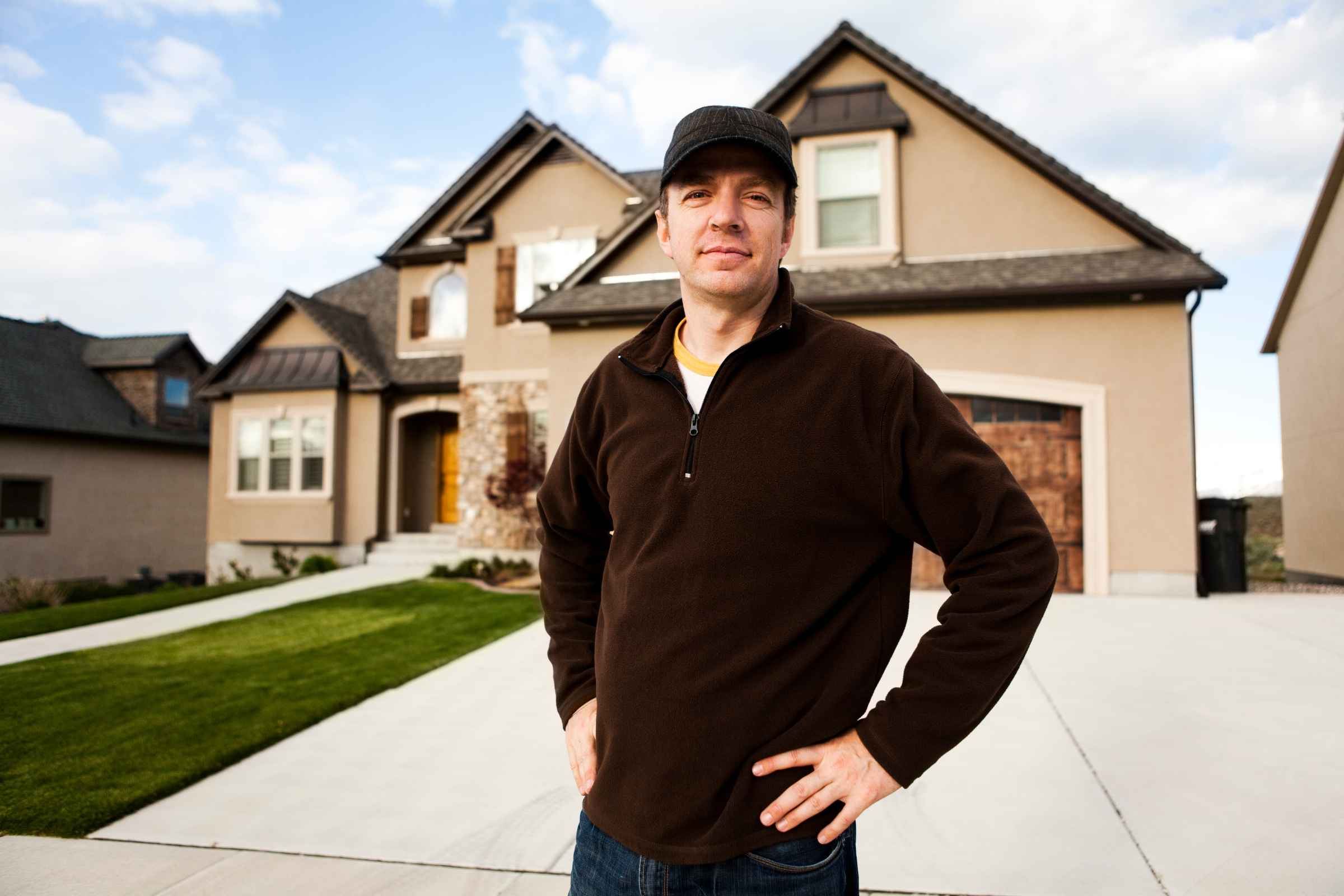 Un homme portant une casquette, debout devant l'allée de son garage